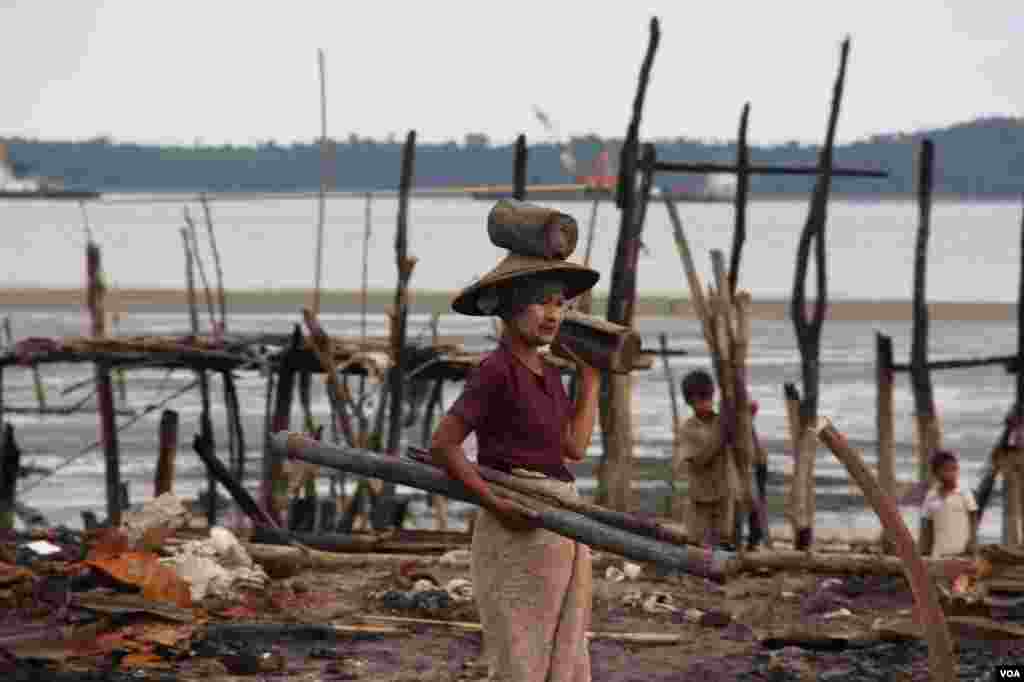 2012年11月，在被焚毁的若开邦穆斯林社区皎漂(Kyauk Phyu)，一位妇女搬着捡来的废木。 (D. Schearf/VOA)