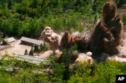 FILE - Smoke and debris rise in the air as barracks buildings for guards and tunneling workers at North Korea's nuclear test site are blown up at Punggye-ri, North Hamgyong Province, North Korea, May 24, 2018.