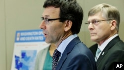 Washington Attorney General Bob Ferguson, center, talks to reporters Sept. 28, 2017, in Seattle, as Seattle City Attorney Pete Holmes, right, looks on.