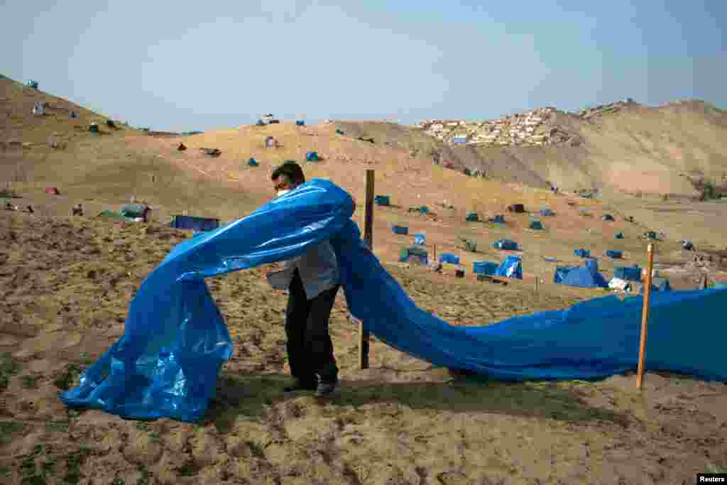 A man marks a plot of land on the Morro Solar as people are occupying the area amidst the outbreak of the COVID-19, in Chorrillos, Peru, April 10, 2021.