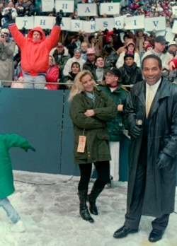 FILE - O.J. Simpson stands with Nicole Brown Simpson while broadcasting on the sidelines during the Thanksgiving Day NFL football game in Irving, Texas, Nov. 25, 1993.