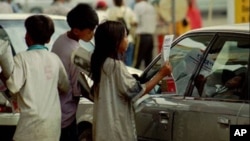 Cambodian child vendors sell newspapers to a car driver at a retail gas station in Phnom Penh, file photo. 