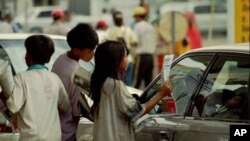 Cambodian child vendors sell newspapers to a car driver at a retail gaz station in Phnom Penh, Cambodia. 