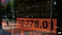 Woman walks past electronic board showing Hong Kong share index, July 3, 2013.