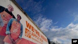 FILE - A sign announcing hiring is displayed in the parking lot of a Home Depot, Feb. 22, 2021, in Cockeysville, Md. 