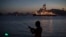 FILE - A man holds his fishing rod, carrying an illuminated bobber, on the shore of Guanabara Bay where Petrobras operates its ultra-deep drilling vessel Laguna Star NS-44, in Niteroi, Brazil.