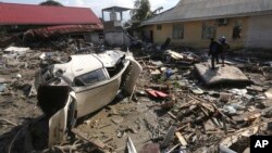 People survey the damage following a massive earthquake and tsunami at Talise beach in Palu, Central Sulawesi, Indonesia, Monday, Oct. 1, 2018. 