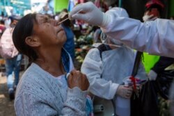 A health worker takes a sample from a vendor to test for COVID-19 at La Terminal market in Guatemala City, May 21, 2020.