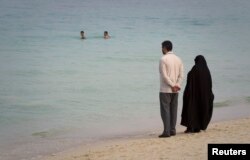 FILE - A couple watches swimmers as they stand on the beach of Kish Island, 1,250 kilometers (777 miles) south of Tehran, April 26, 2011.