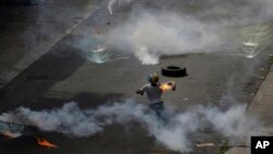 A demonstrator throws a fire bomb at security forces launching tear gas at an anti-government protest demanding Venezuelan President Nicolas Maduro open a so-called humanitarian corridor for the delivery of medicine and food aid, in Caracas, Venezuela, Monday, May 22, 2017. 