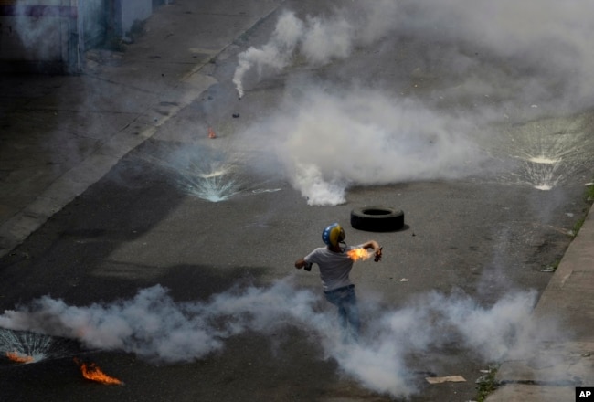 Un manifestante lanza una bomba molotov a la policía que lanzó gases lacrimógenos a una protesta de médicos y estudiantes de medicina que exigían la apertura de un canal humanitario en Caracas.