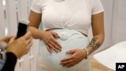 A model wears the Owlet Band pregnancy monitor at the Owlet booth at CES International, Jan. 9, 2019, in Las Vegas. The device can track fetal heart rate, kicks and contractions. 