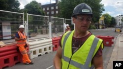 FILE - In this photo taken June 24, 2016, Iosif Achim, a 32-year-old Romanian logistics manager, right, stands at a construction site while being interviewed in London.