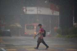 8일 말레이시아 쿠알라룸푸르에서 마스크를 쓴 청년이 폭우 속에서 음식을 배달하고 있다.