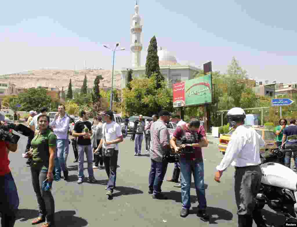 Journalists wait at al-Rawda Square, near a road that leads to the national security building where a bomb killed at least three top aides to President Assad, after access to the area was blocked in Damascus July 18, 2012.