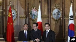 Chinese Premier Wen Jiabao, Japanese Prime Minister Naoto Kan and South Korean President Lee Myung-bak, left to right, shake hands at their joint news conference in Tokyo, May 22, 2011