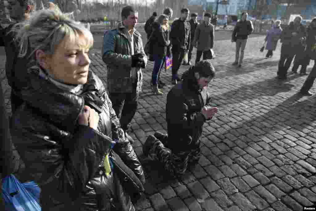 A man kneels as he pays his respects to fallen anti-Yanukovych protesters near Kyiv's Independence Square, Feb. 24, 2014.