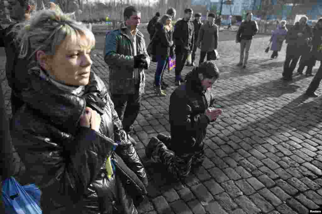 A man kneels as he pays his respects to fallen anti-Yanukovych protesters near Kyiv&#39;s Independence Square, Feb. 24, 2014. 