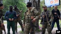 Pro-Russian gunmen listen to instructions from their commander, center, behind barricades in Slovyansk, eastern Ukraine, Friday, May 2, 2014. Ukraine launched what appeared to be its first major assault against pro-Russian forces who have seized governmen