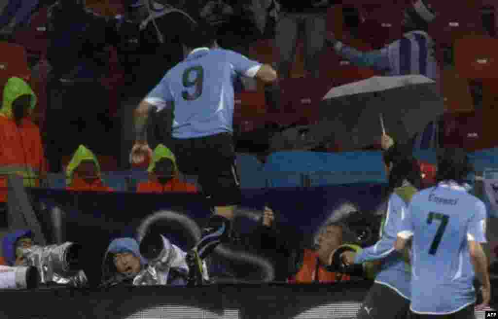 Уругвая Луис Суарес (Уругвай), в центре, перепрыгивает фотографов, радуясь после своего гола в ворота Южной Корей в матче на «Мандела Бэй Стадион» в Порт-Элизабет, Южная Африка. Суббота, 26 июня 2010г. (AP Photo / Ли Цзинь)