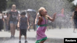 Seorang gadis cilik berlari di tengah percikan air dari selang di depan sebuah memorial di Washington, D.C., saat temperatur di ibukota mencapai lebih dari 38 derajat Celcius (foto: dok).