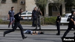 Israeli police officers stand near the body of an alleged Palestinian assailant at the scene of a stabbing in Pisgat Zeev, an Israeli settlement on the northern edge of Jerusalem, Oct. 12, 2015.