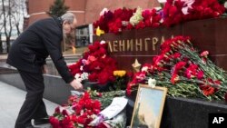 Un hombre coloca flores por las víctimas del atentado en una estación del metro de San Petersburgo, Rusia. El monumento corresponde a la tumba del Soldado Desconocido en Moscú, que tiene el rótulo de Leningrado, como era llamada antes San Petersburgo.