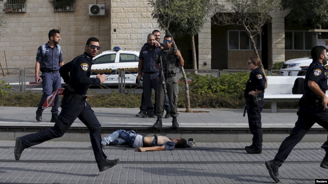 Sarkaal booliis Israeli ah oo ag taagan meydka qof Falastiini ah oo ay toogteen, markii uu weerarka minidida qaaday kadib.