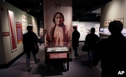 FILE - Visitors pass a portrait featuring Sitting Bull, part of the Hall of North American Indian exhibit, at the Peabody Museum of Archaeology & Ethnology at Harvard University in Cambridge, Massachusetts, Oct. 13, 2016.