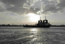 En esta foto publicada por la Autoridad del Canal de Suez, dos remolcadores se acercan al Ever Given, de propiedad japonesa y con bandera de Panamá, que se encuentra encajado bloqueando el Canal de Suez, el domingo 28 de marzo de 2021.