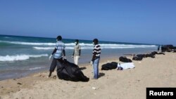 FILE - Public service workers bag bodies of migrants that drowned off Tripoli's coast, Aug. 25, 2014. 