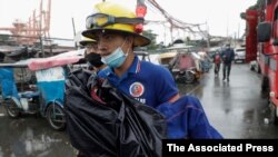 Un rescatista lleva en brazos a un niño enfermo durante la evacuación de una población costera en Manila, Filipinas, el domingo 1 de noviembre de 2020. Un supertifón arremetió contra el este de Filipinas. Cerca de un millón de personas fueron evacuadas.