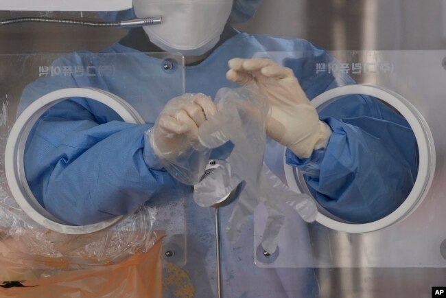 A medical worker wears plastic gloves at a temporary screening clinic for the coronavirus in Seoul, South Korea, Monday, Nov. 29, 2021. (AP Photo/Lee Jin-man)