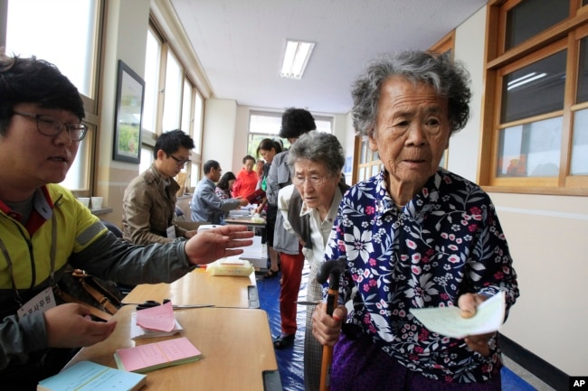 FILE - Elderly women wait to cast their ballots in local elections at a polling station in Nonsan, South Korea, June 4, 2014. In South Korea, 100 working-age people fund the social benefits for 37 citizens.