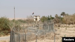 FILE - An Iraqi border policeman stands guard on a watch tower on the Iraqi-Syrian border at the Abu Kamal border crossing, the main border post between Iraq and Syria, Sept. 8, 2012.