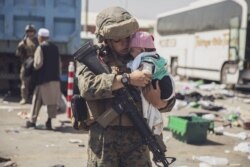 A U.S. Marine carries a baby during an evacuation at Hamid Karzai International Airport, in Kabul, Afghanistan, Aug. 28. (US Marine Corps photo)