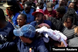 FILE - A migrant from Cameroon holds his baby while trying to enter the Siglo XXI immigrant detention center to request humanitarian visas, issued by the Mexican government, to continue to the U.S., in Tapachula, Mexico, July 5, 2019.