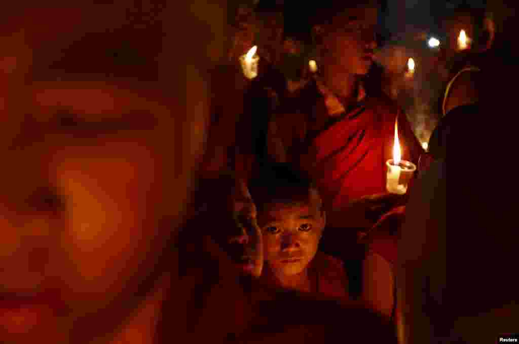 Buddhist monks holding candles offer prayers for the victims of earthquakes in Kathmandu, Nepal.