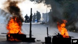 Bolivarian National Police stand behind a burning roadblock set up by anti-government protesters who are showing support for a mutiny by some National Guard soldiers in the Cotiza neighborhood of Caracas, Venezuela, Jan. 21, 2019. 