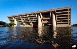 A reflecting pool sits in a large plaza on the walk up to Dallas City Hall, a building designed by architect I.M. Pei, in Dallas, Thursday, May 16, 2019. (AP Photo/Tony Gutierrez)