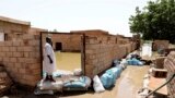 FILE: A man passes on the side of a flooded road in the town of Alkadro, about (20 km) north of the capital Khartoum, Sudan, Taken 9.5.2020