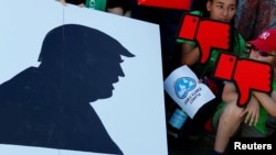 People hold banners as they protest next to the Brandenburg Gate, beside the U.S. embassy, against the U.S. withdrawal from the Paris climate change deal, in Berlin, Germany, June 2, 2017.