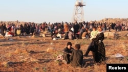 FILE - Syrian refugees, fleeing the violence in Syria, wait to enter Turkey on the Syrian-Turkish border in Shamm Alqrain village, northern countryside of Aleppo.