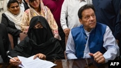 FILE - Pakistani former Prime Minister Imran Khan, right, and his wife, Bushra Bibi, sign surety bonds for bail in various cases at a registrar's office in Lahore, Pakistan, on July 17, 2023.