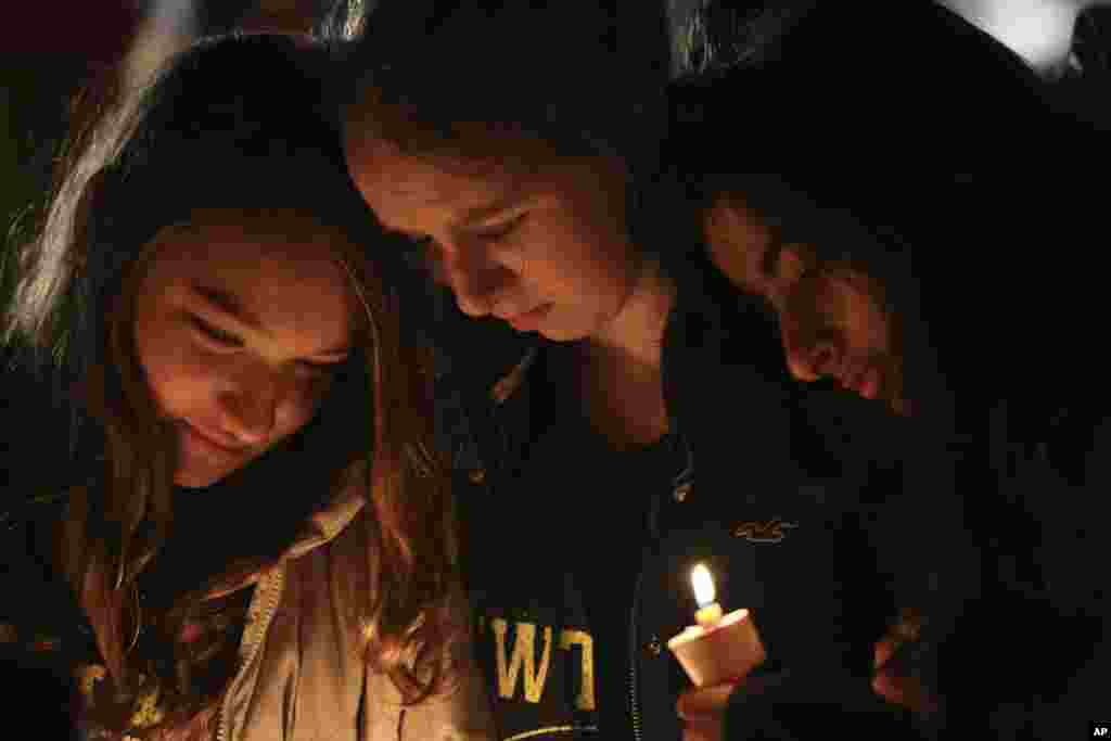 Kate Suba (kiri), Jaden Albrecht (tengah) dan Simran Chand mengheningkan cipta untuk memberikan penghormatan saat berlangsungnya doa bersama untuk para korban penembakan di SD Sandy Hook, Newtown, Connecticut, 16 Desember 2012. (AP Photo/Mary Altaffer)