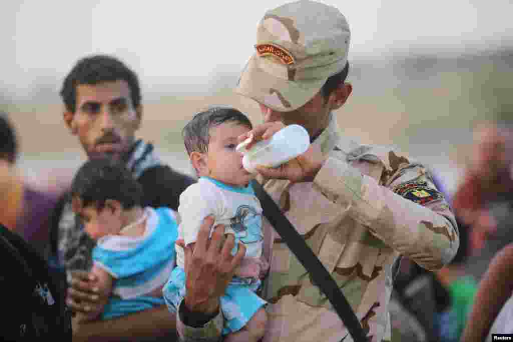An Iraqi soldier cares for a displaced child from Ramadi at the outskirts of Baghdad, May 19, 2015.