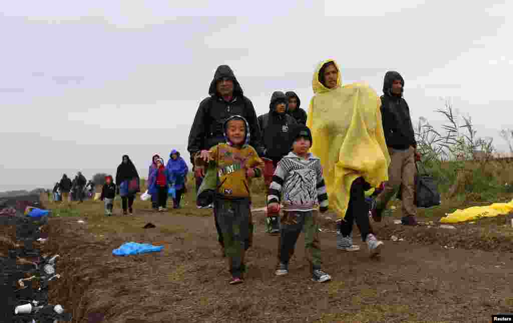 Migrantes caminham por uma estrada de terra batida, junto a ponto de recolha, em Roszke, Hungria, Set. 10, 2015. A pol+icia húngara capturou um record de 3.321 migrantes no dia 9, acrescentando aos outros 3.313 detidos na Quinta-feira, 3 de Setembro.