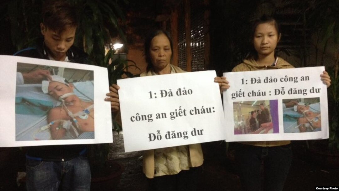 Mẹ và anh chị của nạn nhân Đỗ Đăng Dư cầm biểu ngữ phản đối. (Facebook: Dung Truong)