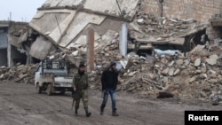 Rebel fighters walk near damaged buildings in al-Rai town, northern Aleppo countryside, Syria, Dec. 30, 2016. 