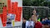 FILE - Hong Kong pro-democracy activists hold a placard, at right, that reads "rights activism is not wrong, free Huang Qi" during a protest outside the Chinese Liaison Office in Hong Kong, Jan. 29, 2019. 